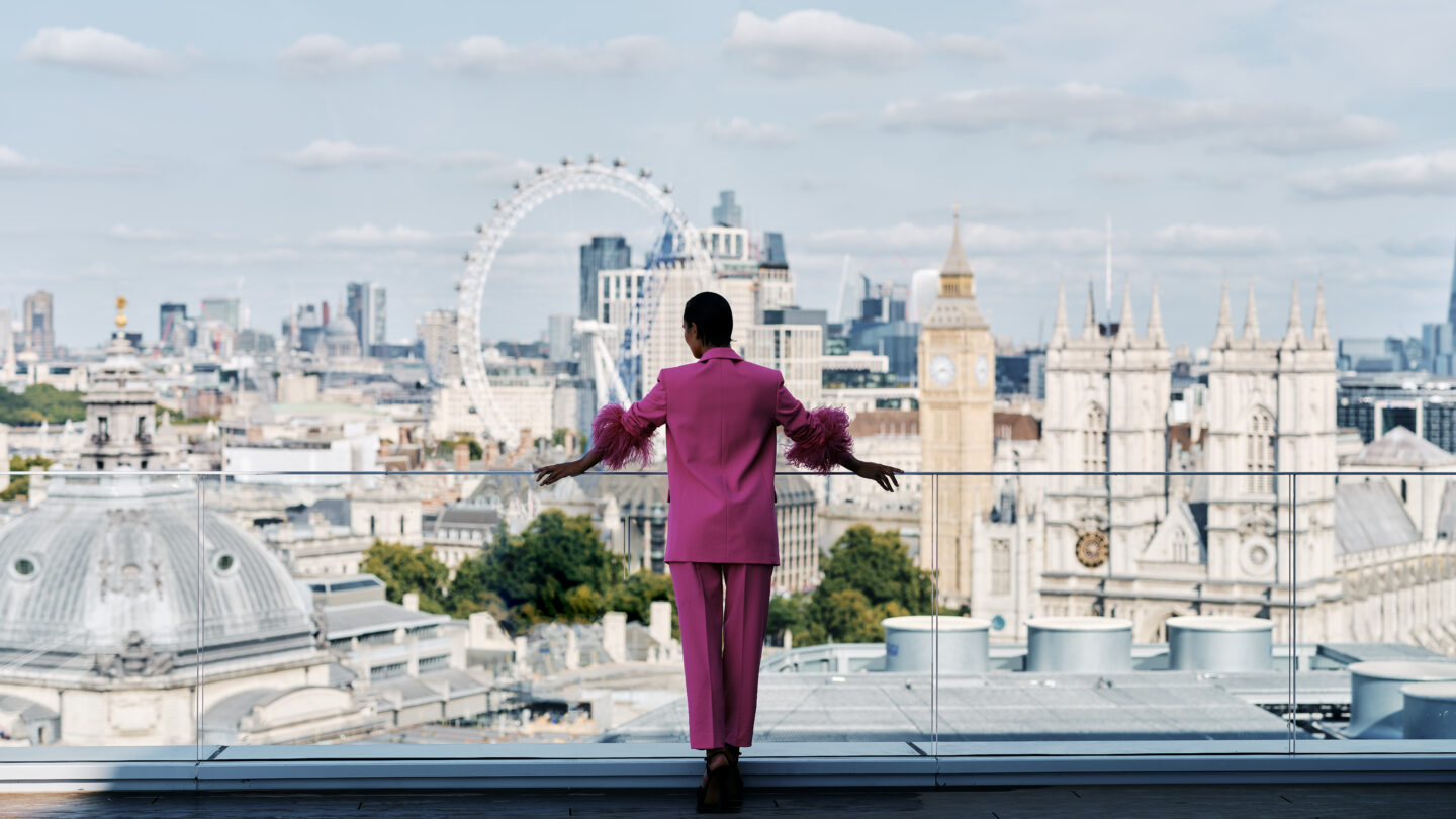 Woman in pink suit looks out over London at Orchard Place